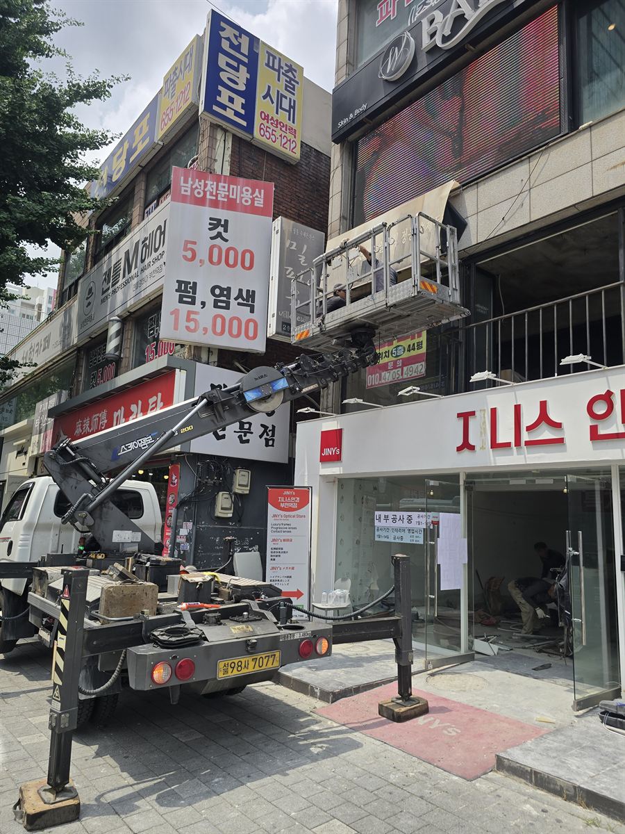 상가 외벽 간판을 스카이차로 작업하는 모습