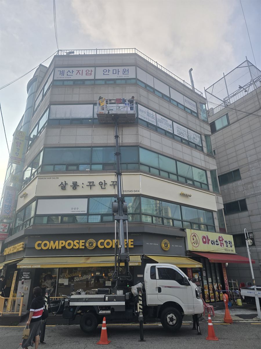 고층 건물 외벽 간판을 스카이차로 작업하는 모습